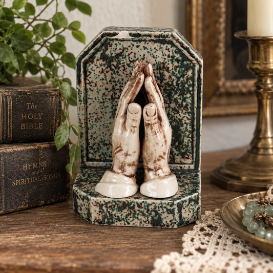 Styled vintage ceramic praying hands religious decor with antique Bible and brass accents
