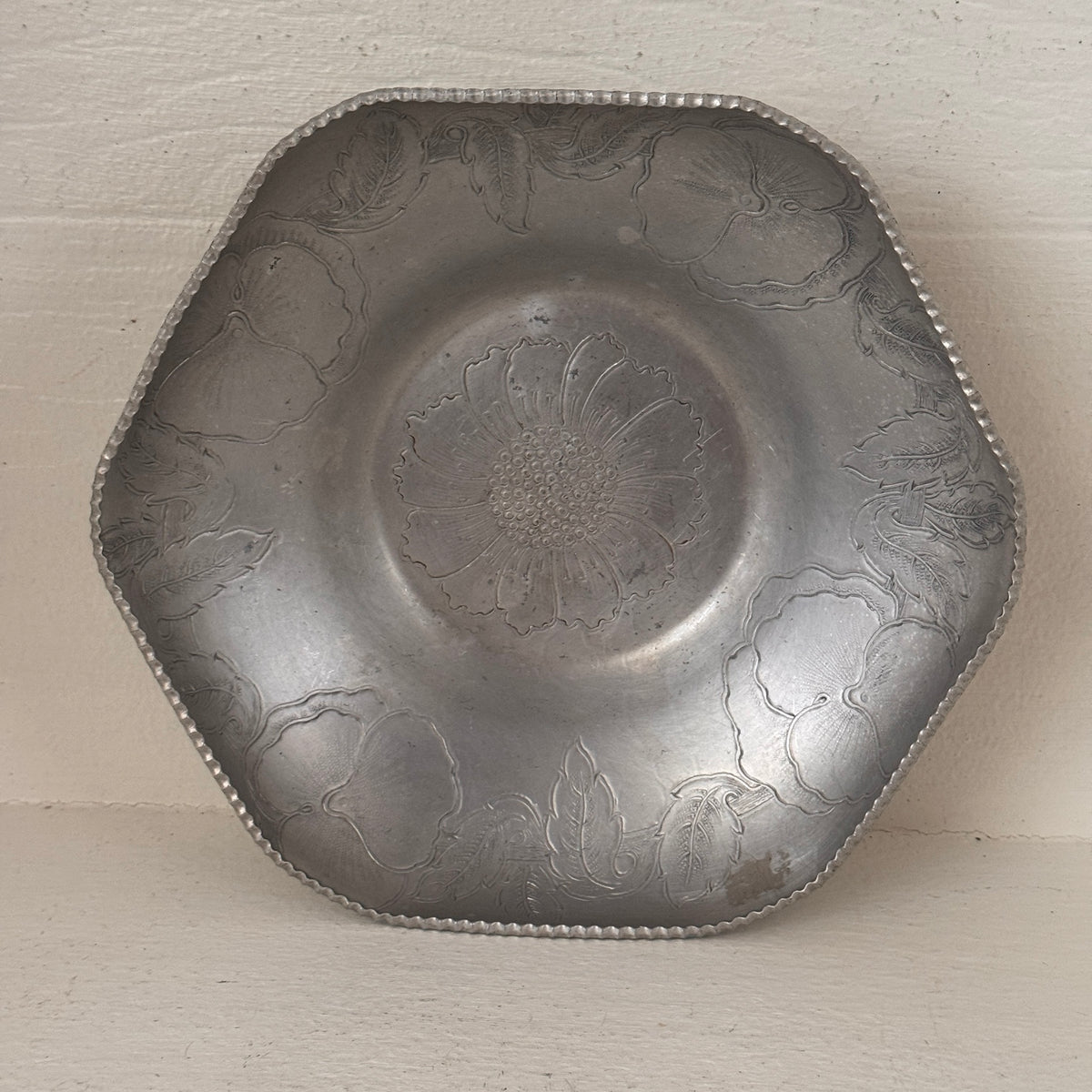 Top view of vintage hand wrought aluminum bowl with floral engraving and beaded rim